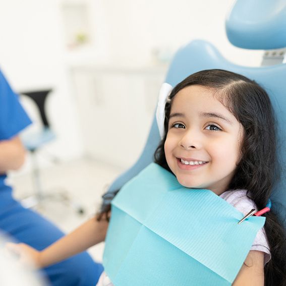 Little girl sitting in dental chair and smiling