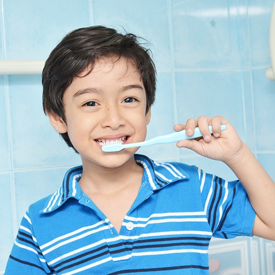 Little boy with striped blue shirt brushing his teeth