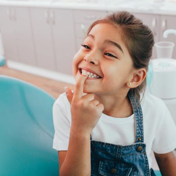 Happy young dental patient pointing at her teeth