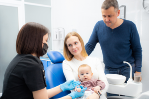 a young couple taking their infant to visit the dentist